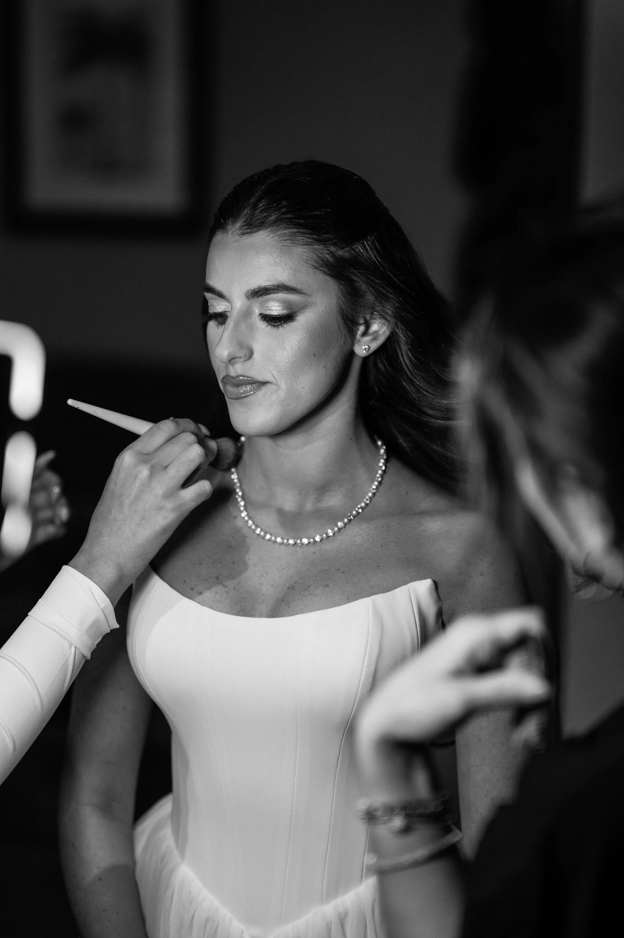 Black-and-white portrait of the bride receiving makeup in soft light at Crest Hollow, Woodbury, Long Island.