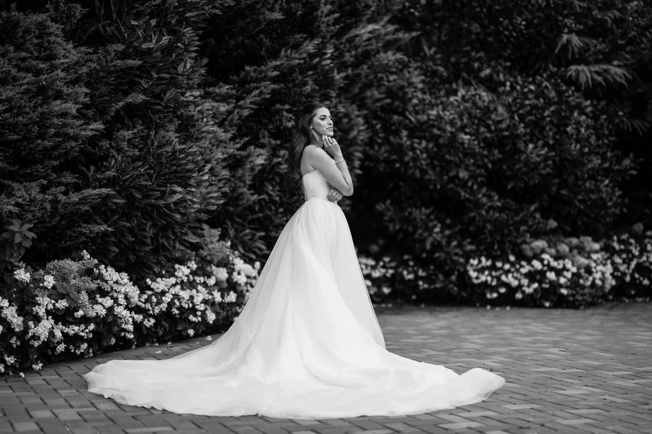 Black-and-white bridal profile with a sculptural train spread across the garden path at Crest Hollow, Woodbury, Long Island.