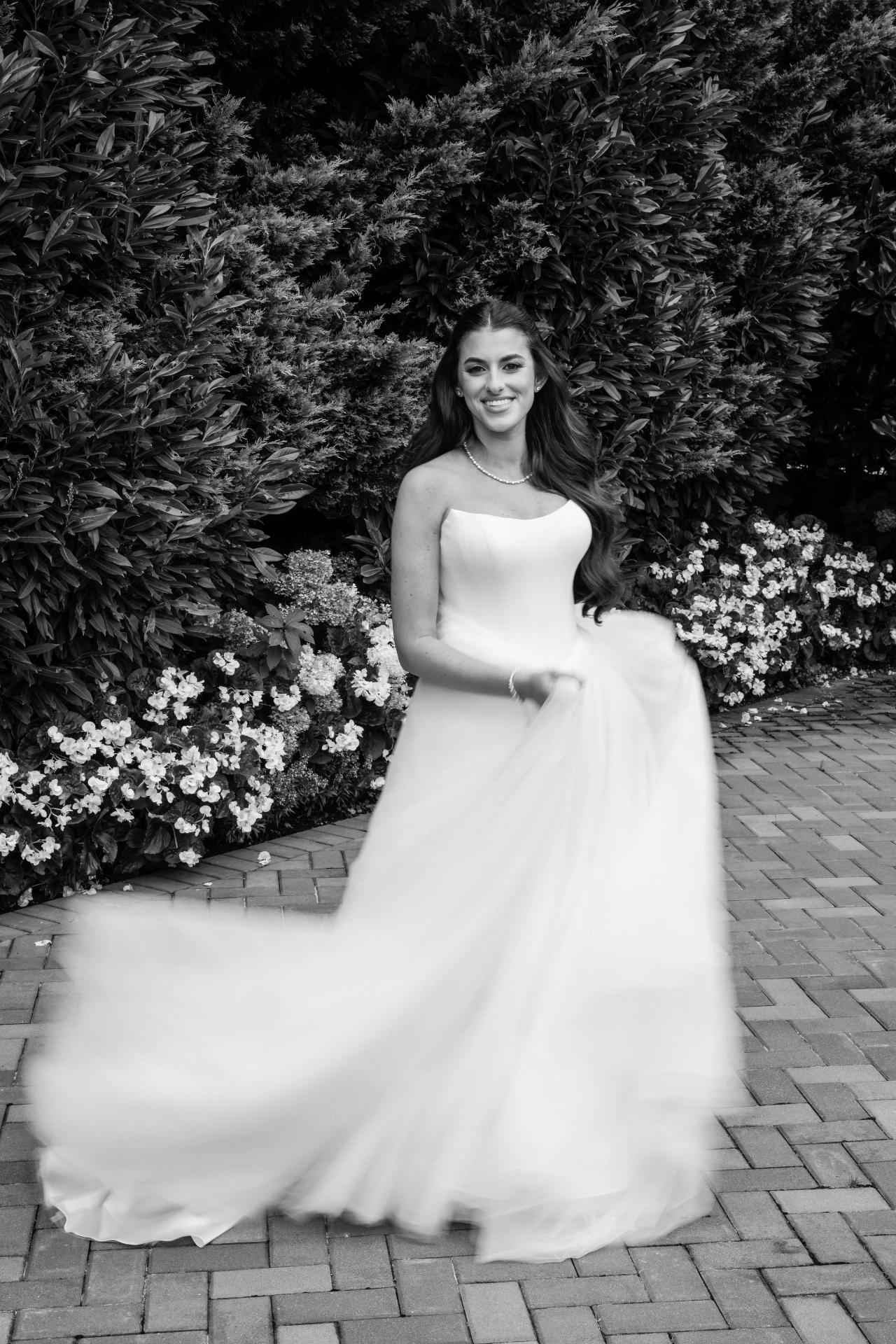 Black-and-white motion-blur portrait of the smiling bride sweeping her gown at Crest Hollow, Woodbury, Long Island.
