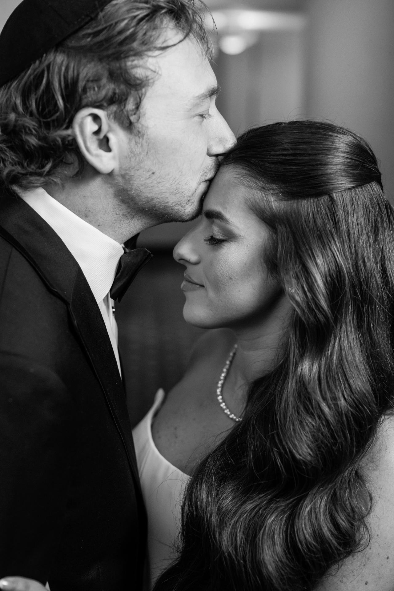 Black-and-white close portrait of the groom kissing the forehead of the bride at Crest Hollow, Woodbury, Long Island.