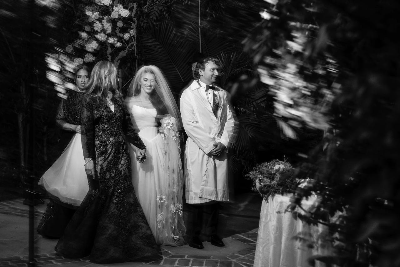 Black-and-white bride and groom beneath the chuppah seen through streaked, blurred foliage at Crest Hollow, Woodbury, Long Island.