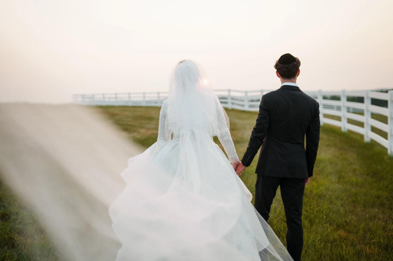 Bride and groom walking hand in hand toward the sunset with a flowing veil and soft foreground blur at their Baltimore wedding. Wedding photography at Vignon Manor Farm, Baltimore, MD.