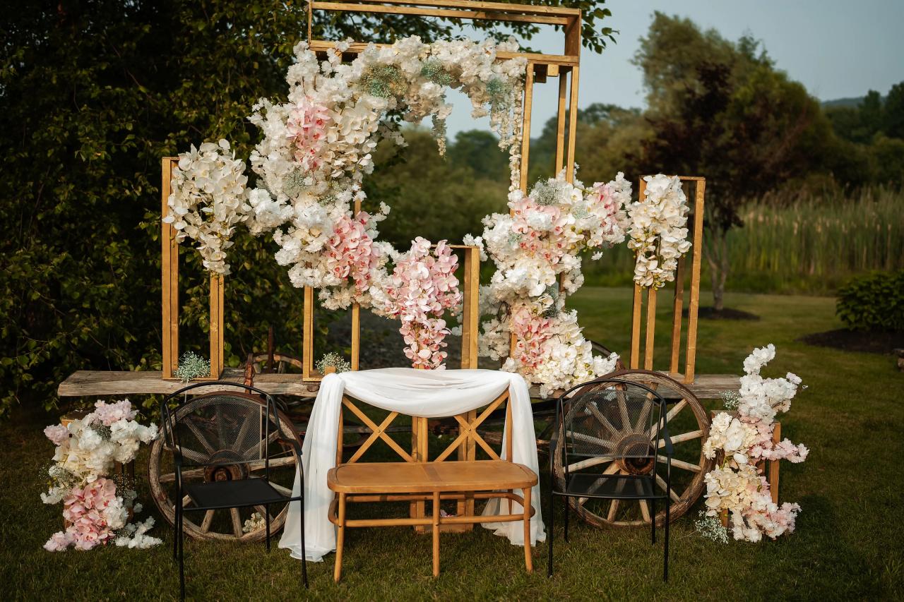 Floral canopy and chairs at an outdoor simcha ceremony setup with abundant white and blush flower arrangements. Wedding photography at The Barn At Indian Ridge, Highland, NY.