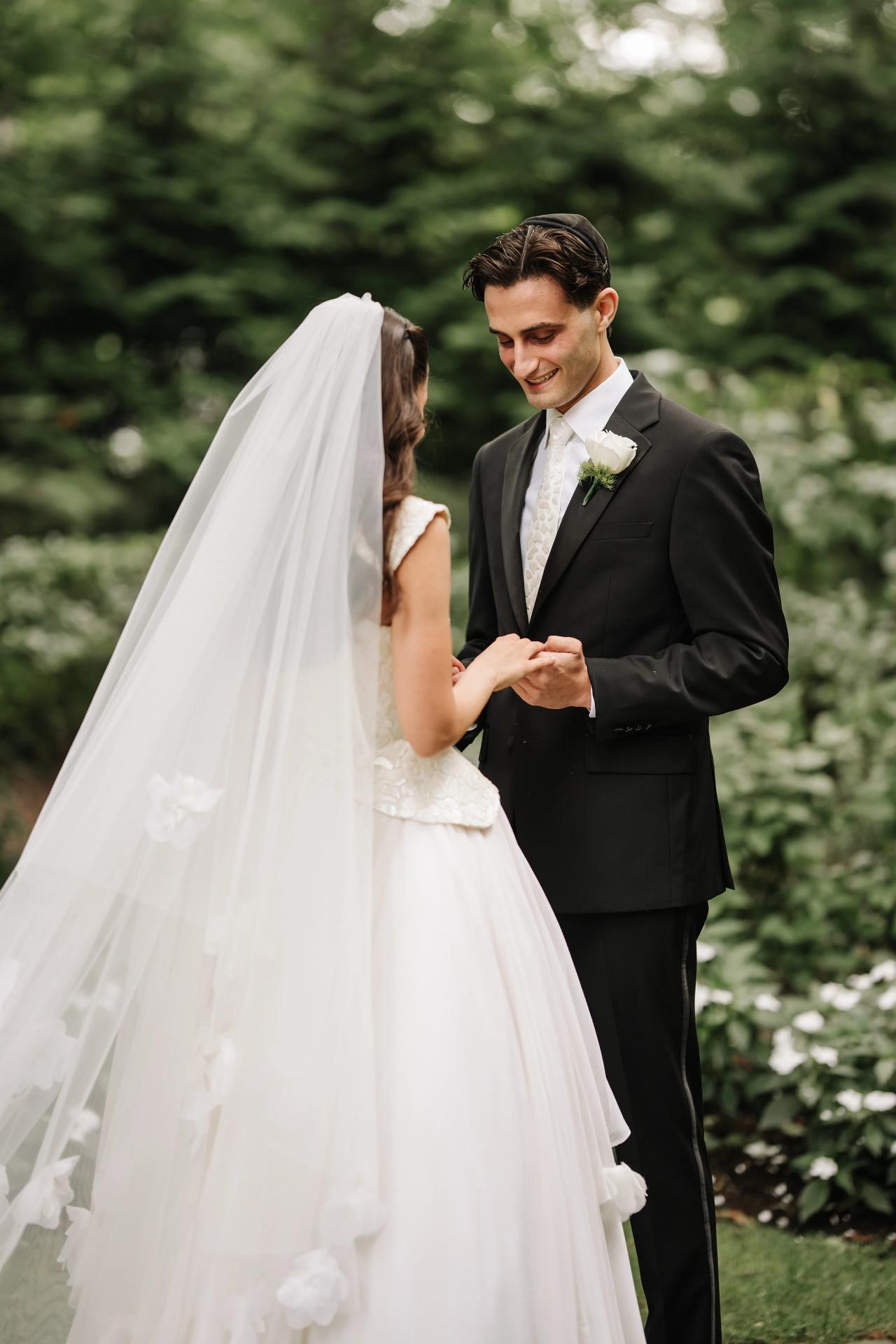 Outdoor wedding portrait of a bride and groom standing close in garden greenery, the bride’s veil in front as they share an intimate moment. Wedding photography at Crystal Plaza, Livingston, NJ.