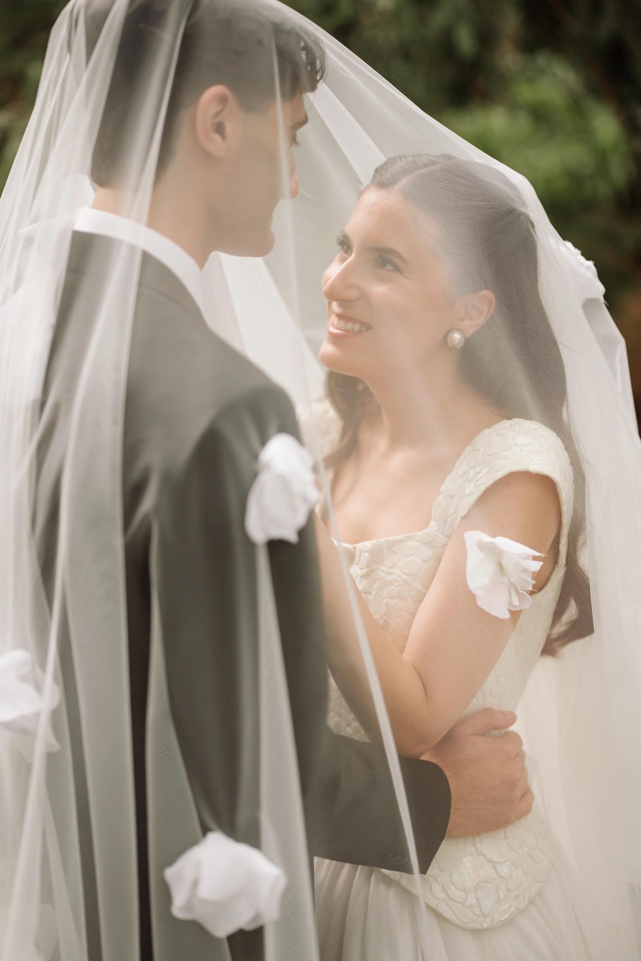 Bride and groom sharing an intimate moment in soft backlight, the bride’s veil draped over the scene as they smile at each other. Wedding photography at Crystal Plaza, Livingston, NJ.