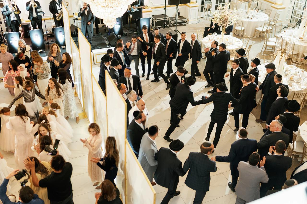 Wide overhead view of a packed ballroom dance floor during a wedding simcha, with guests in formal attire celebrating and clapping. Wedding photography at Crystal Plaza, Livingston, NJ.