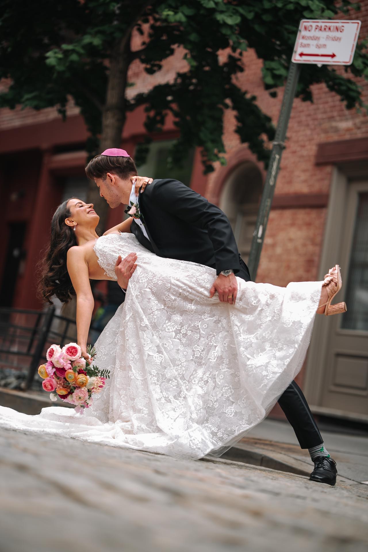 Bride and groom in an outdoor moment of embrace, bride’s bouquet visible as they walk together in bright daylight. Wedding photography at Tribeca Rooftop + 360°, New York, NY.