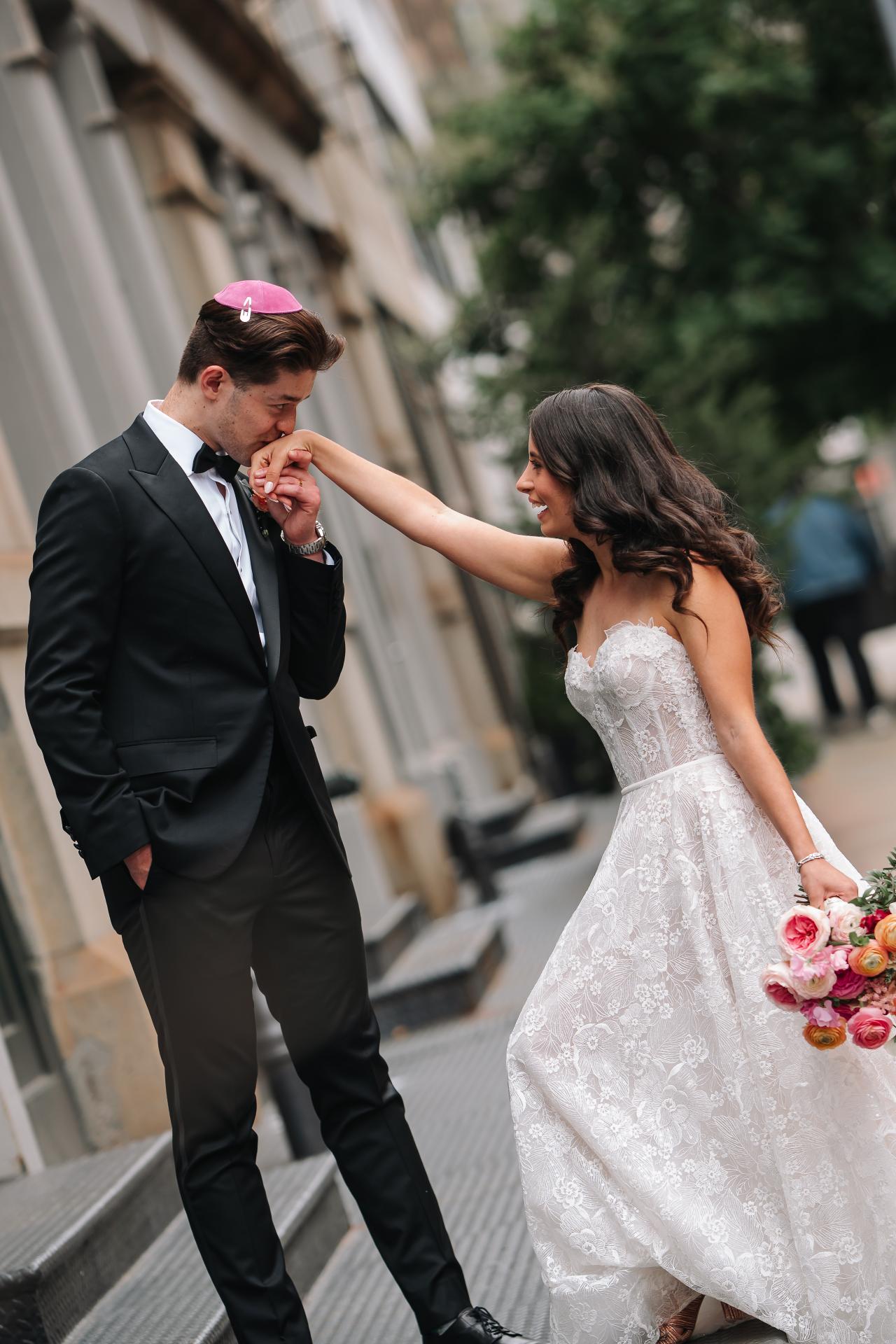 Bride and groom smiling intimately as the groom holds his head near the bride’s hand outdoors, with a bouquet visible in the bride’s other hand. Wedding photography at Tribeca Rooftop + 360°, New York, NY.