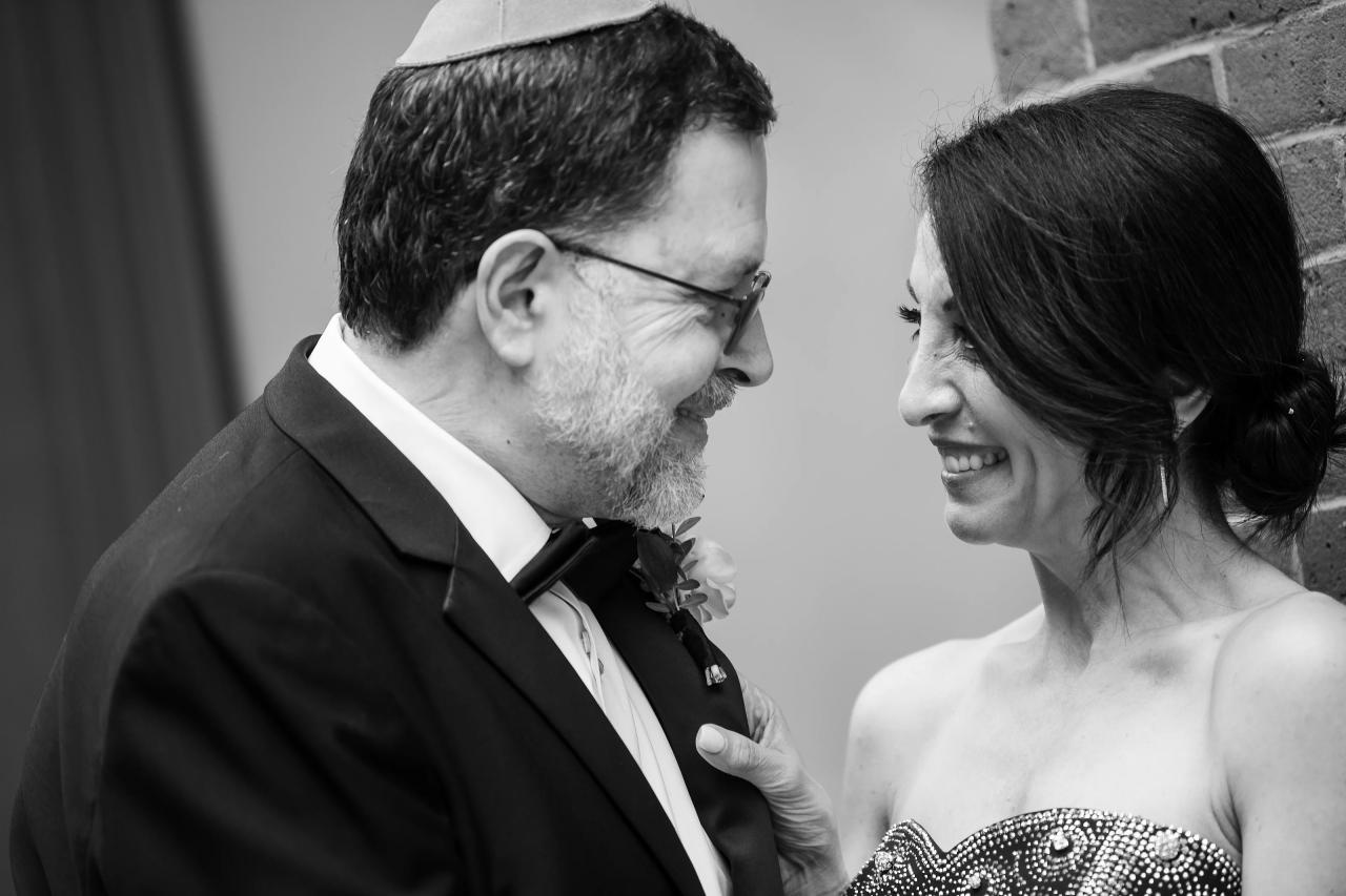 Black-and-white close-up of a bride and groom smiling as they lean in during the badeken, hands near the bride’s shoulder, intimate candle-like emotion. Wedding photography at Tribeca Rooftop + 360°, New York, NY.