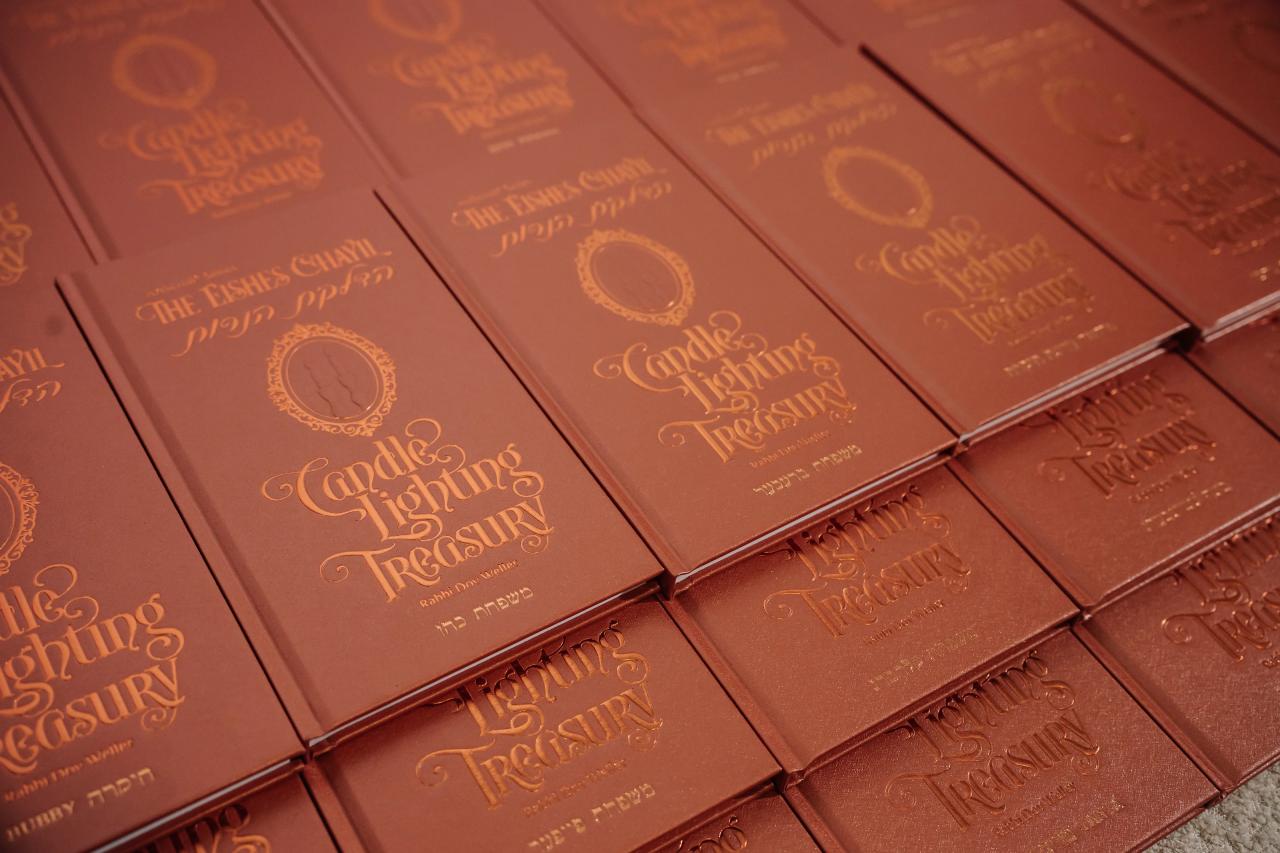 Brown keepsake books with gold lettering arranged in overlapping rows at the bar mitzvah reception. Bar Mitzvah photography at Hilton Garden Inn Springfield, Springfield, NJ.