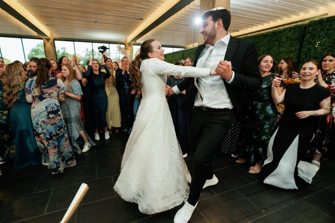 Wedding couple dancing together joyfully on a tiled floor while guests surround them and watch, indoor venue with bright window light. Wedding photography at Bellworks, Holmdel, NJ.