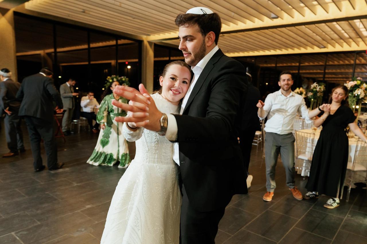 Bride and groom on the dance floor taking a close, playful selfie while guests celebrate in the background under warm lighting. Wedding photography at Bellworks, Holmdel, NJ.