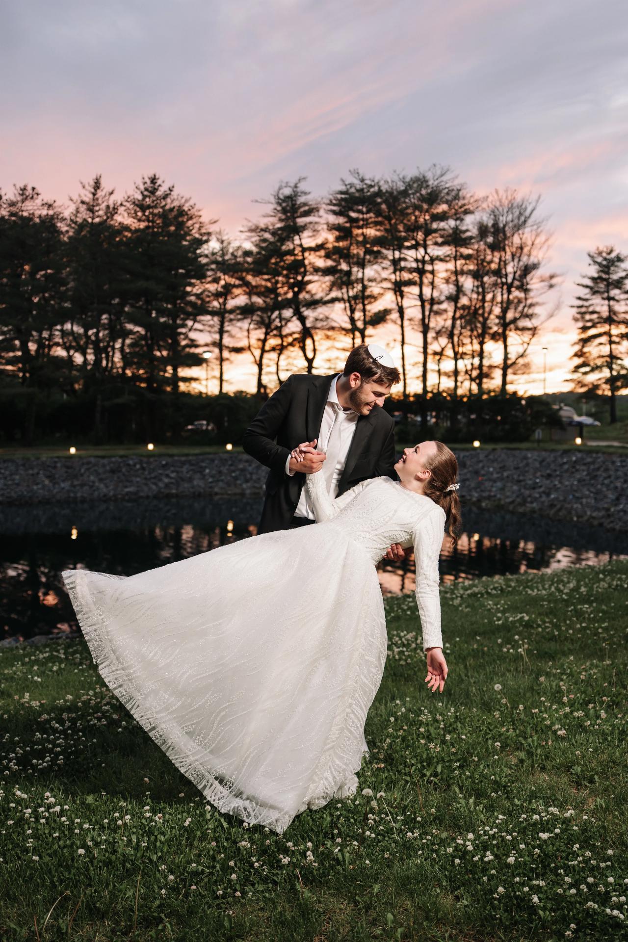 Bride and groom spinning outdoors at sunset on a garden lawn, bride’s white veil flowing and flared in the air. Wedding photography at Bellworks, Holmdel, NJ.