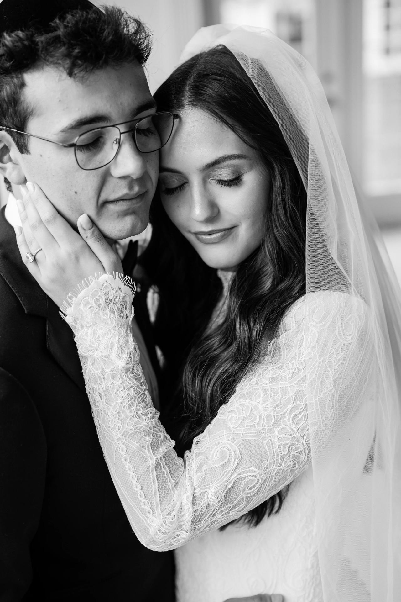 Black-and-white close-up wedding portrait of a bride and groom embracing, bride’s veil framing her face, intimate emotional moment. Wedding photography at Falkirk Estate Country Club, Central Valley, NY.