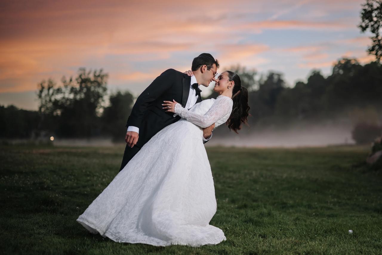 Bride and groom in an intimate embrace outdoors at golden hour, bride’s dress flowing as they slow dance on a grassy field. Wedding photography at Falkirk Estate Country Club, Central Valley, NY.