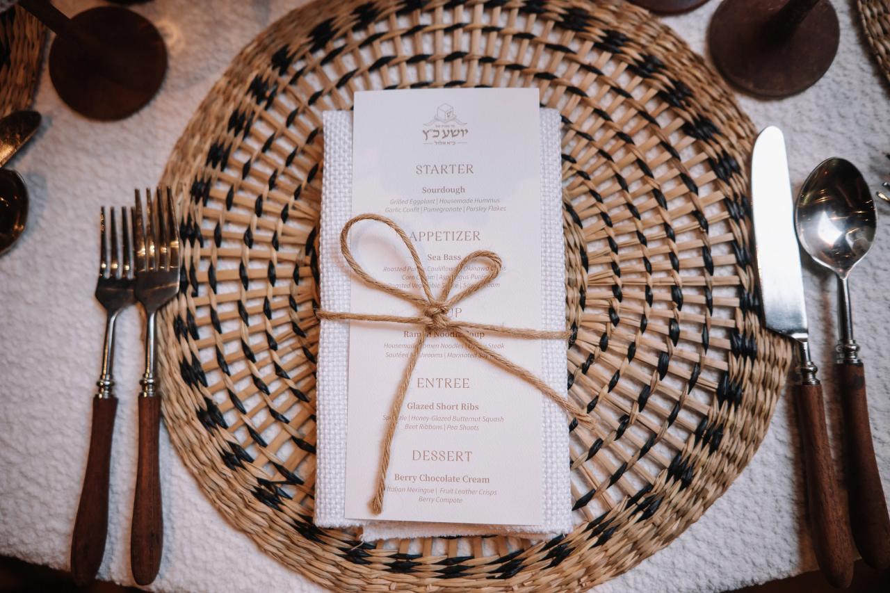 Overhead view of a reception menu card tied with twine on a woven serving tray, with cutlery laid out on the sides. Bar Mitzvah photography at The Arches, Brooklyn, NY.