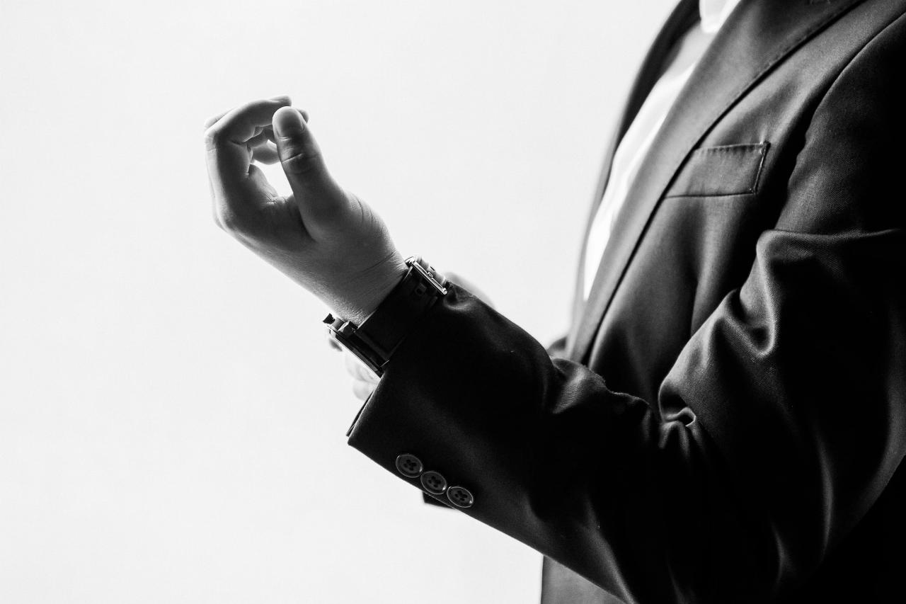 Black-and-white close-up of the Bar Mitzvah boy’s raised arm and suit cuff against a bright white background, minimalist fashion portrait. Bar Mitzvah photography at The Arches, Brooklyn, NY.