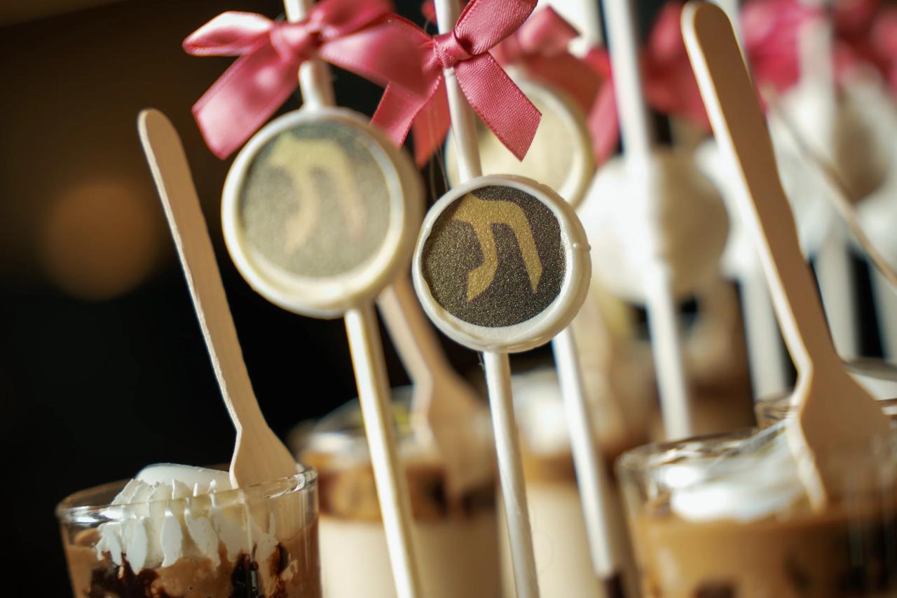 Close-up of a styled dessert and drinks setup with pink ribbon accents and beverage cups on a table.
