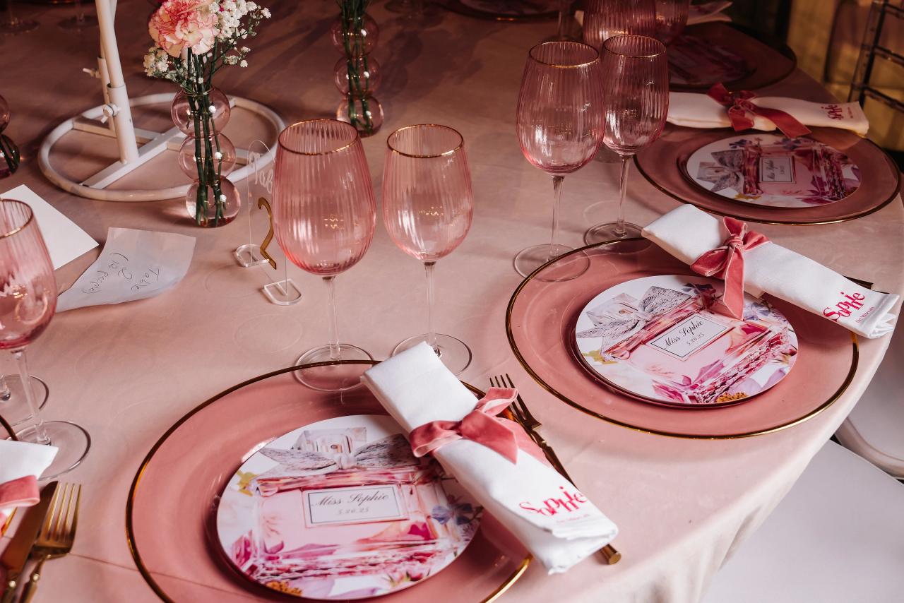 Wedding reception table setting with pink glasses, chargers, napkins, and place cards arranged on the table. Bat Mitzvah photography at Doubletree By Hilton Hotel Fort Lee - George Washington Bridge, Fort Lee, NJ.
