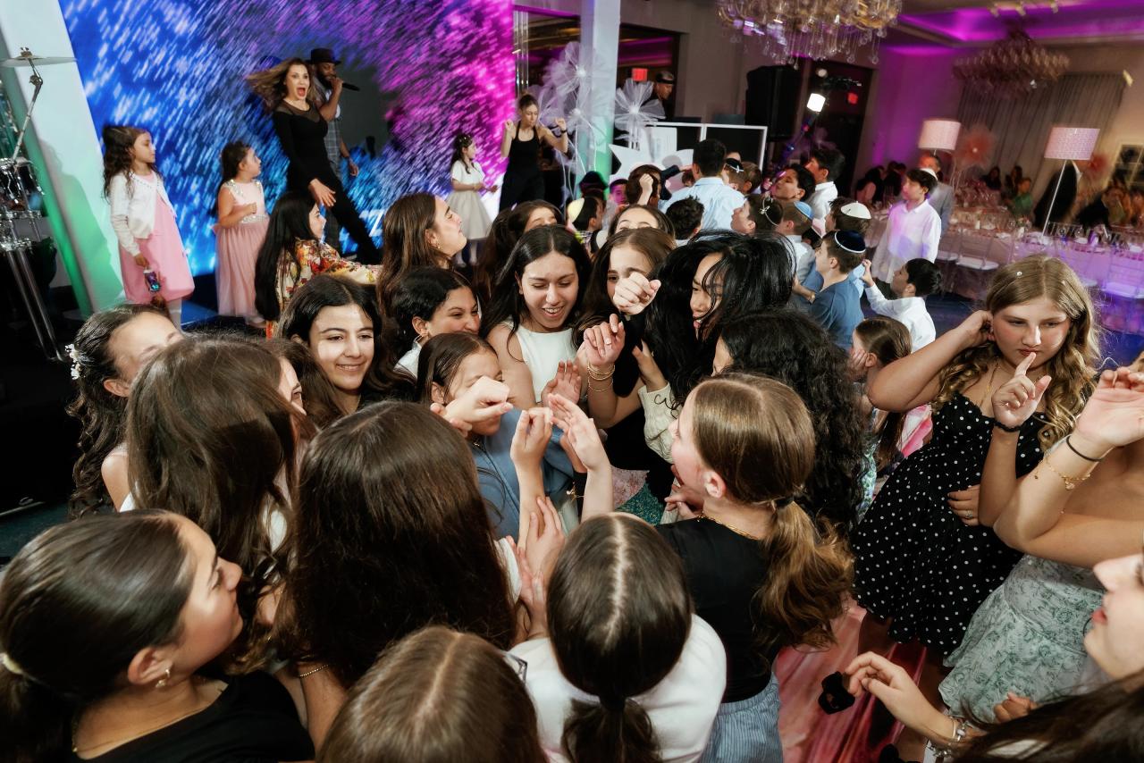 Overhead view of a crowded wedding dance floor with guests celebrating under blue and purple stage lighting and LED backdrop. Bat Mitzvah photography at Doubletree By Hilton Hotel Fort Lee - George Washington Bridge, Fort Lee, NJ.