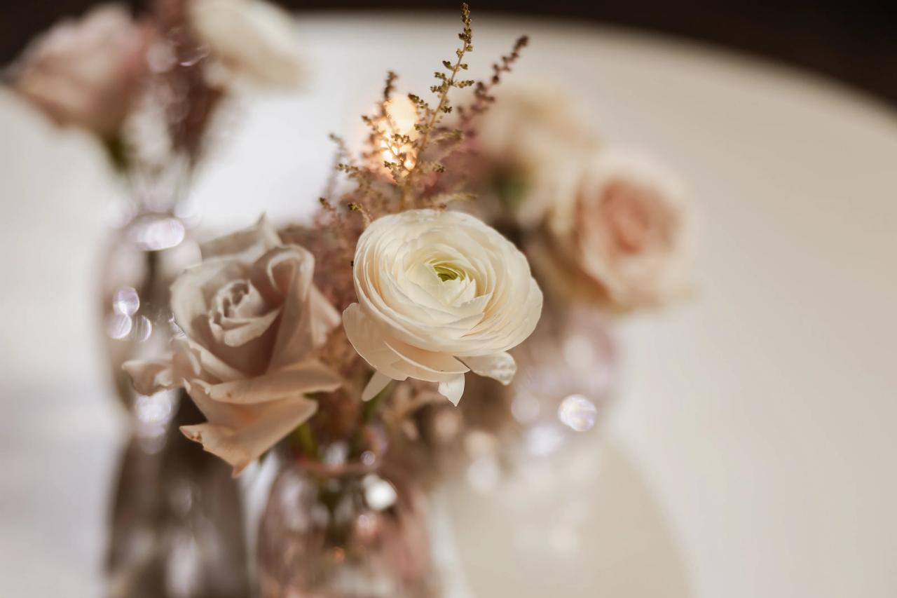 Close-up of a white bloom with shallow depth of field, warm blurred floral arrangements in the background. Bat Mitzvah photography at Bison & Bourbon, Brooklyn, NY.