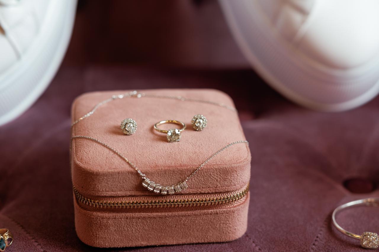 Close-up of several diamond rings on a velvet jewelry box with a necklace chain laid across it. Wedding photography at Riverview Ballroom, Cliffside Park, NJ.