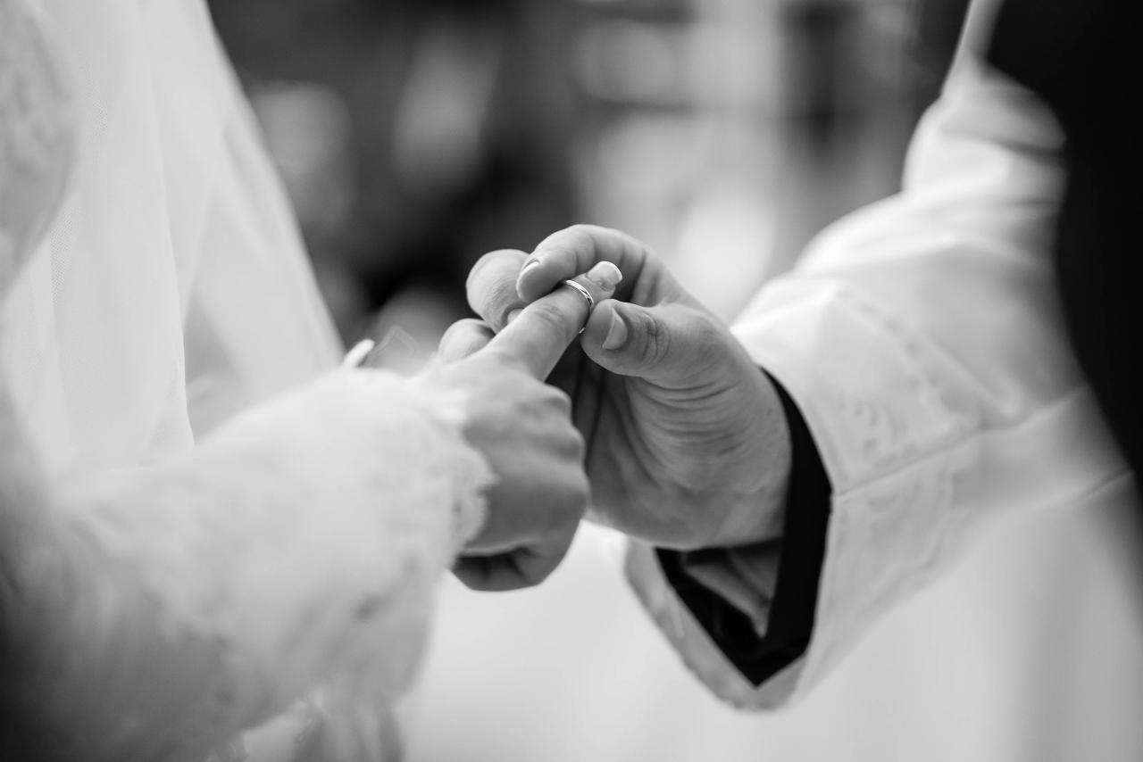 A minimal black-and-white close-up of hands during the wedding ring exchange. Wedding photography at Riverview Ballroom, Cliffside Park, NJ.