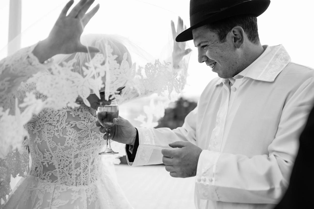 A close black-and-white view of the wedding wine-cup ritual, framed by the bride’s veil. Wedding photography at Riverview Ballroom, Cliffside Park, NJ.