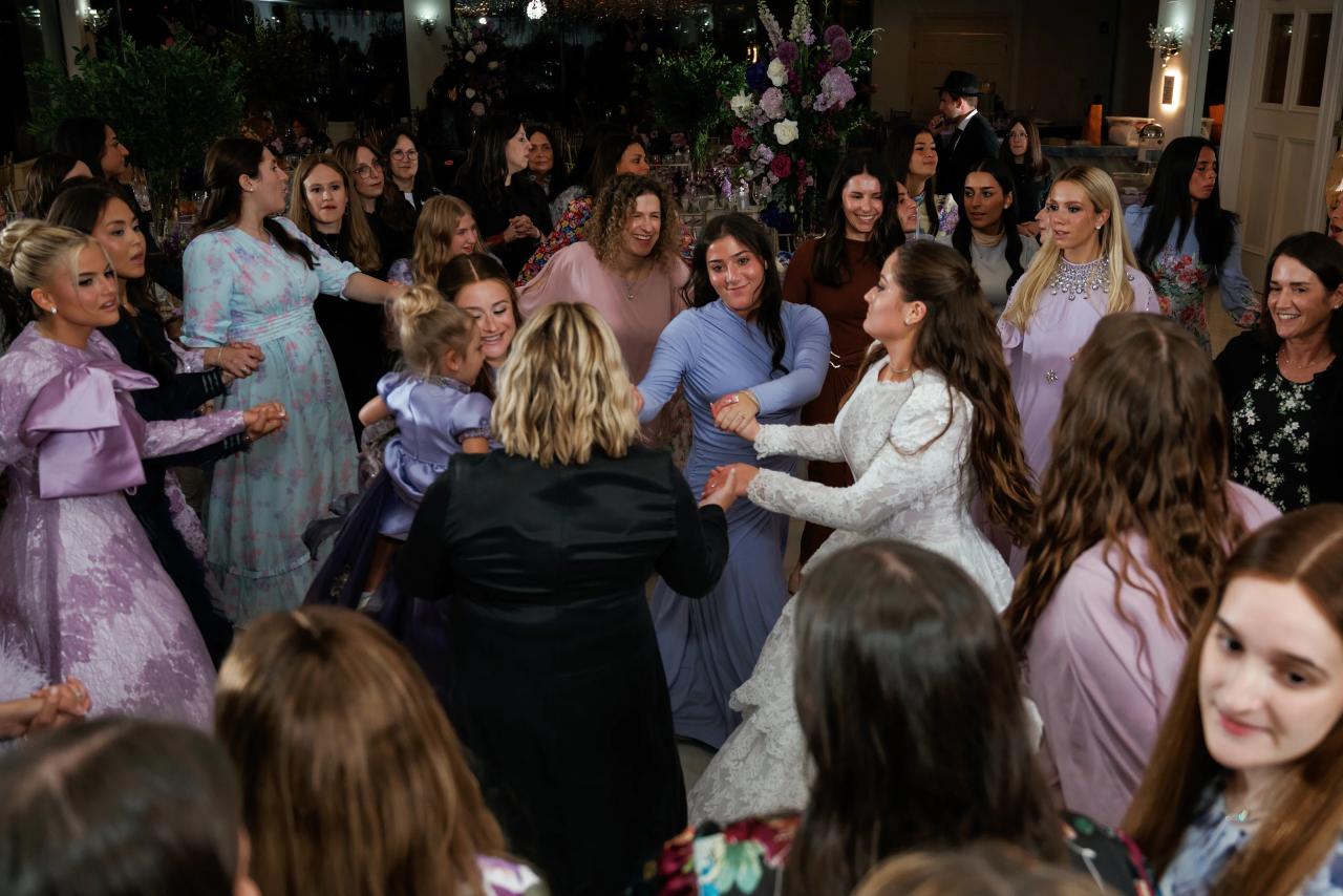 A wide candid view of women dancing together in an energetic wedding circle. Wedding photography at Riverview Ballroom, Cliffside Park, NJ.