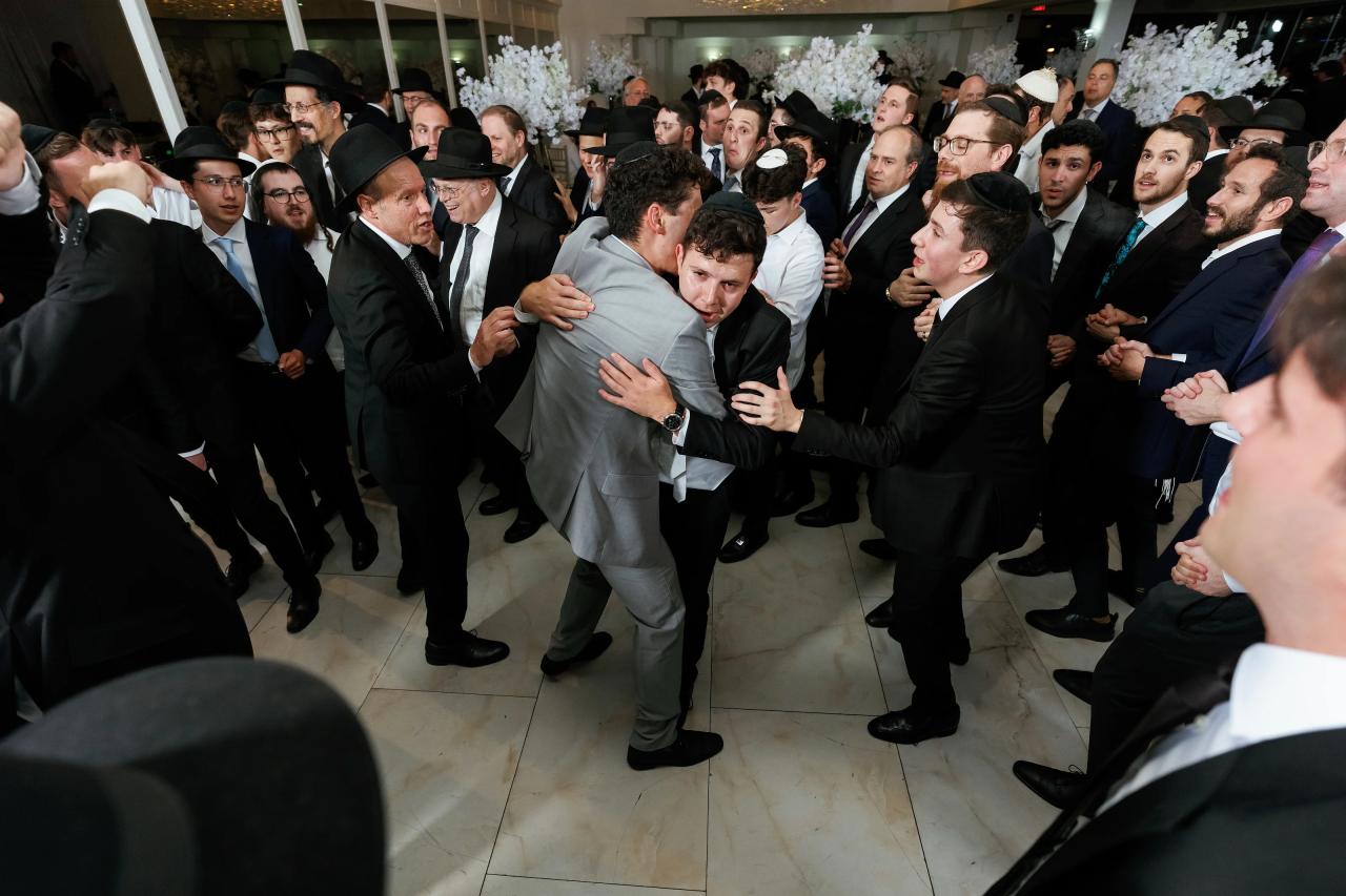 The groom lifted above a close circle of cheering guests on the dance floor. Wedding photography at Riverview Ballroom, Cliffside Park, NJ.