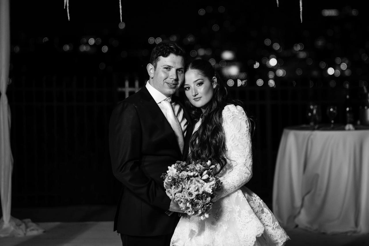 An intimate black-and-white portrait of the newlyweds with soft city-light bokeh behind them. Wedding photography at Riverview Ballroom, Cliffside Park, NJ.