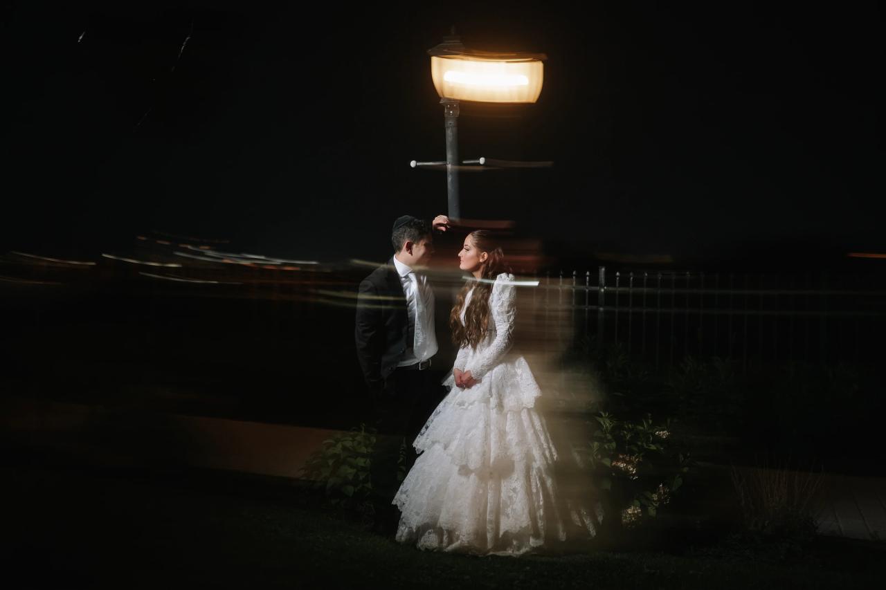 A dreamlike portrait of the newlyweds beneath a glowing garden lamp, with deliberate motion blur. Wedding photography at Riverview Ballroom, Cliffside Park, NJ.