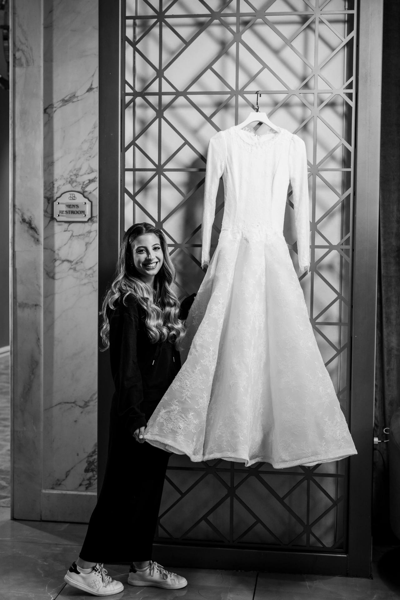 From this Brightstone Hall wedding: black-and-white bridal preparation portrait beside the hanging wedding gown and geometric screen. Wedding photography.