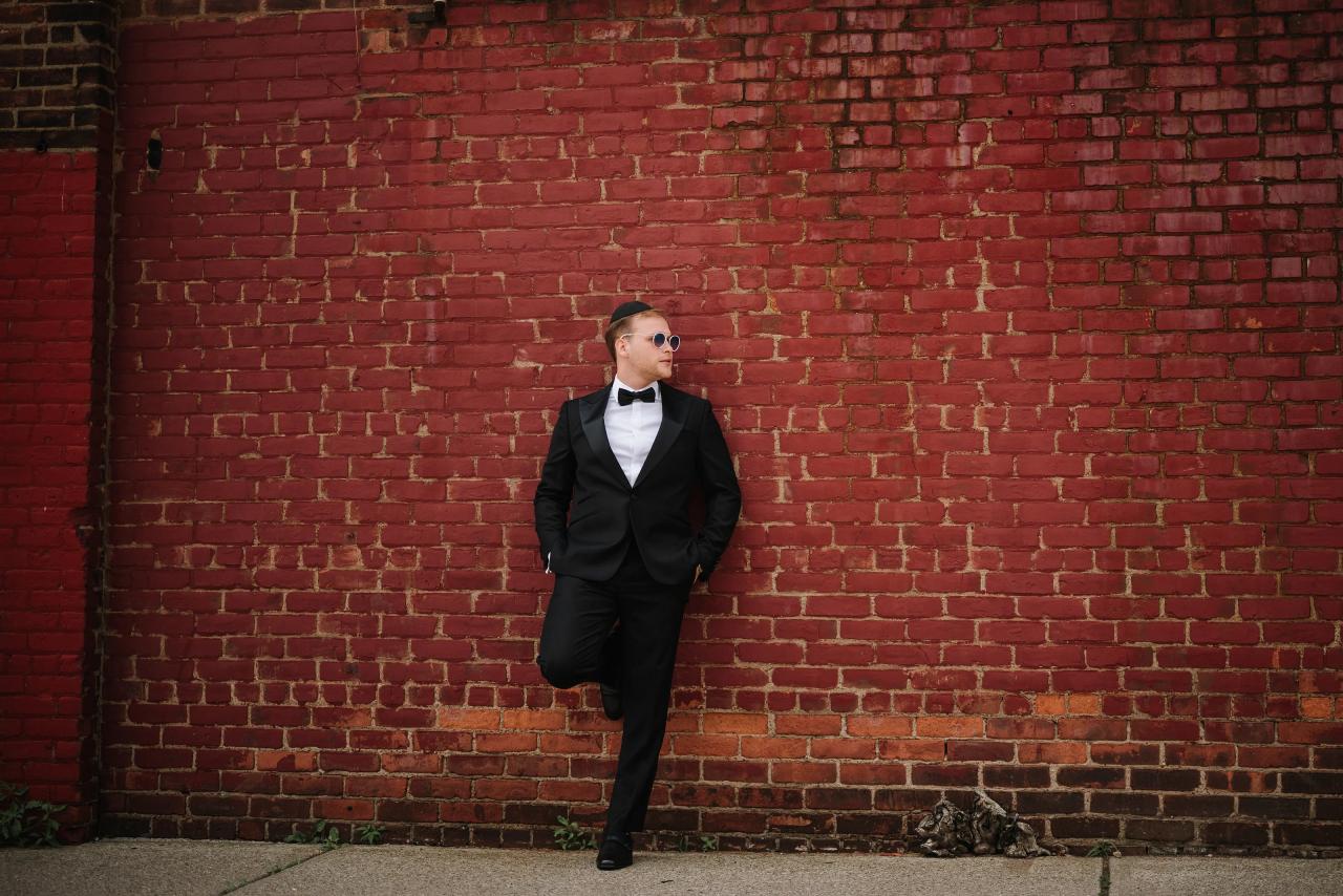 From this Brightstone Hall wedding: groom against textured red brick in a minimalist portrait. Wedding photography.