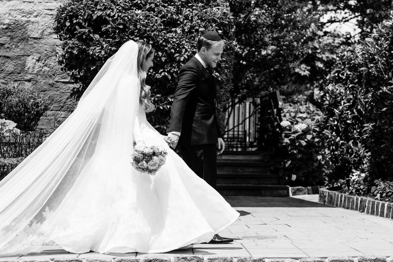 Black-and-white couple portrait with a flowing wedding train beside the entrance. Wedding photography at Brightstone, Passaic, NJ.