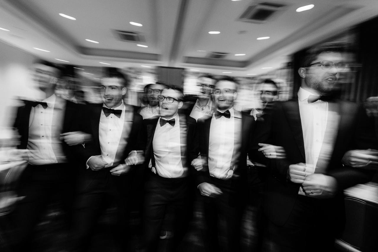 Black-and-white movement among singing friends at the tisch. Wedding photography at Brightstone, Passaic, NJ.