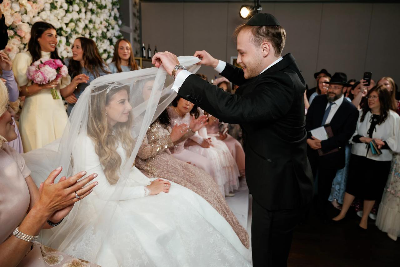 The groom lowers the bride’s veil during the bedeken. Wedding photography at Brightstone, Passaic, NJ.