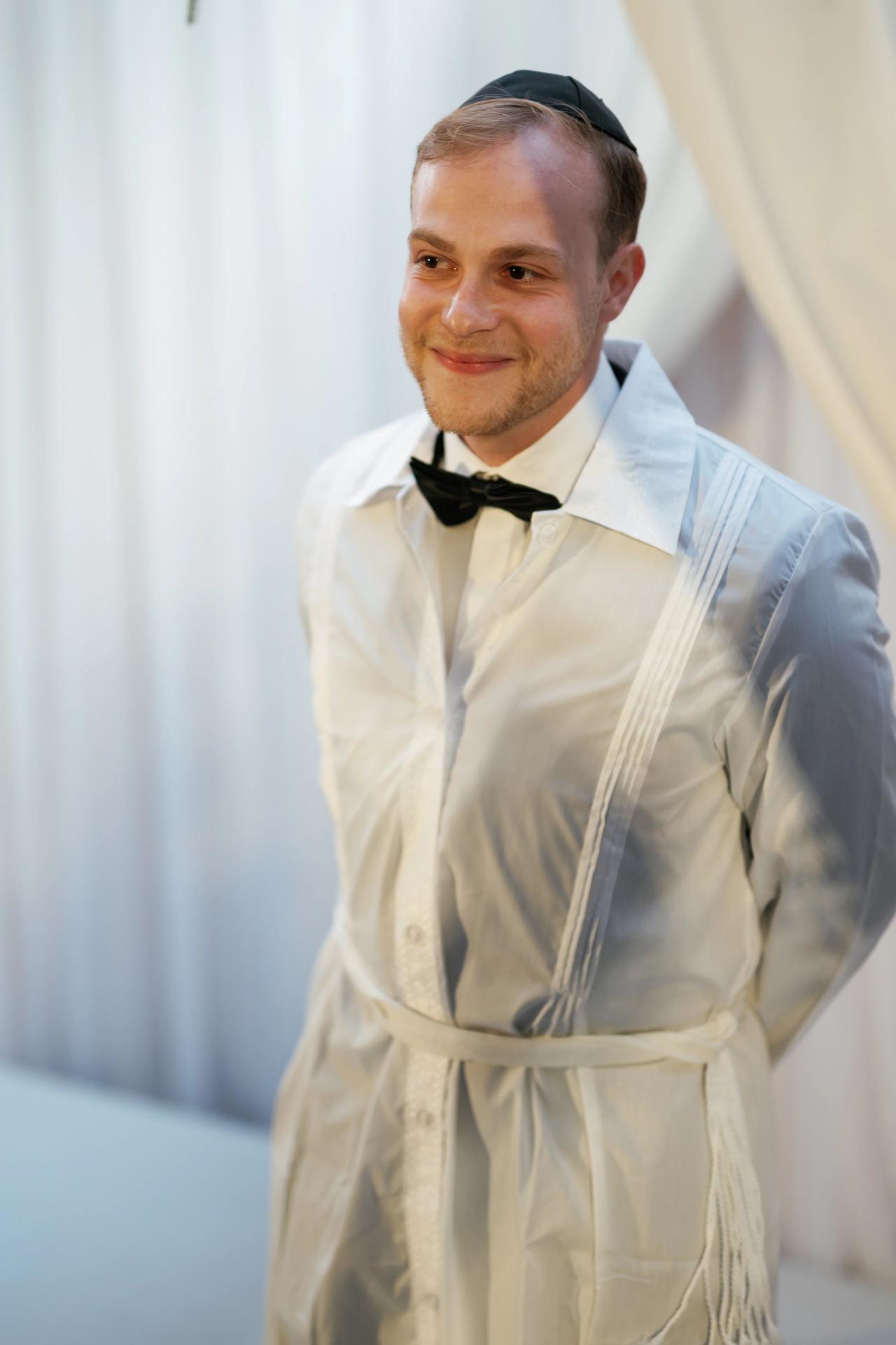 The groom watches the arriving ceremony procession with emotion. Wedding photography at Brightstone, Passaic, NJ.