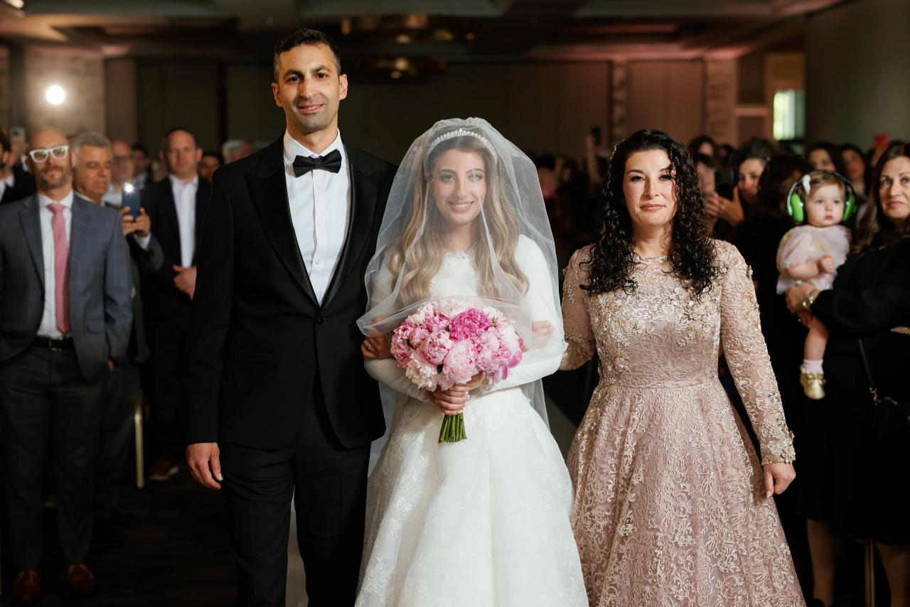 The bride approaches the chuppah surrounded by family. Wedding photography at Brightstone, Passaic, NJ.