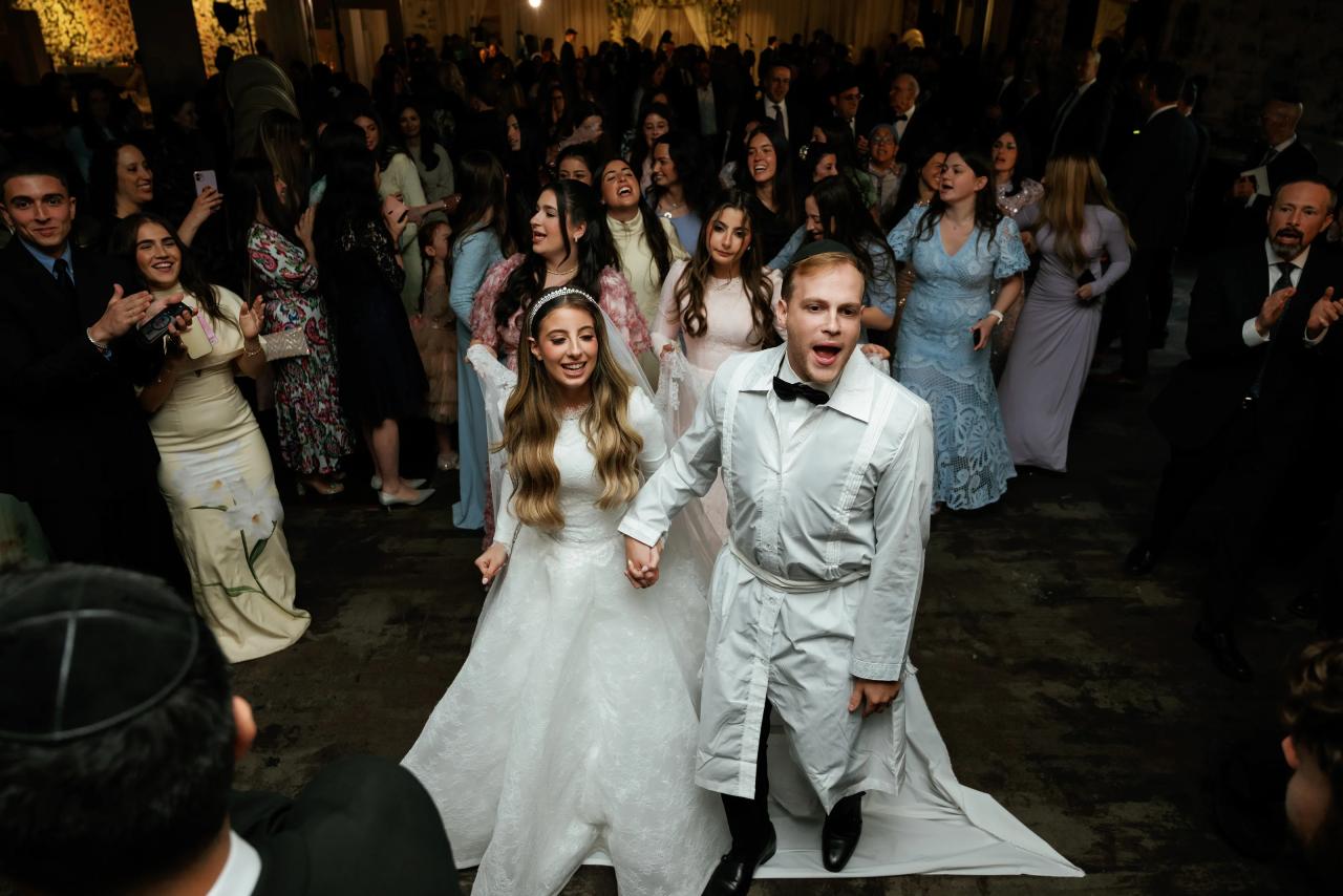 The bride and groom walk out of the ceremony among smiling guests. Wedding photography at Brightstone, Passaic, NJ.