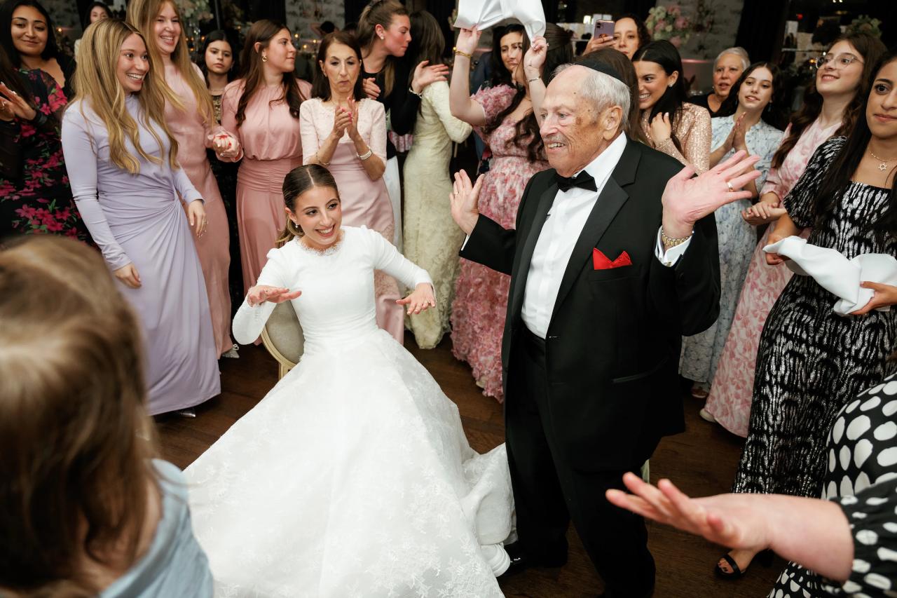 The bride laughs and dances with an older guest. Wedding photography at Brightstone, Passaic, NJ.