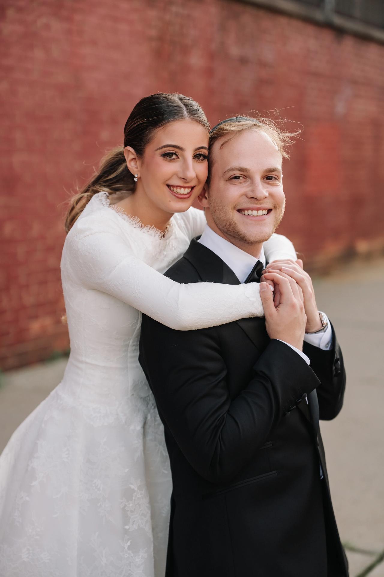 The bride rides on the groom’s back in a playful outdoor portrait. Wedding photography at Brightstone, Passaic, NJ.