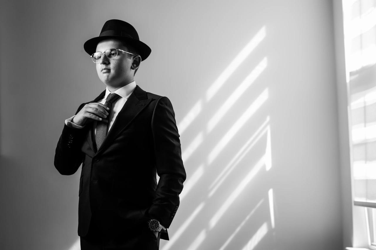 Black-and-white portrait with diagonal bands of window light across a plain wall, before the Eagle Ridge bar mitzvah. Bar Mitzvah photography.