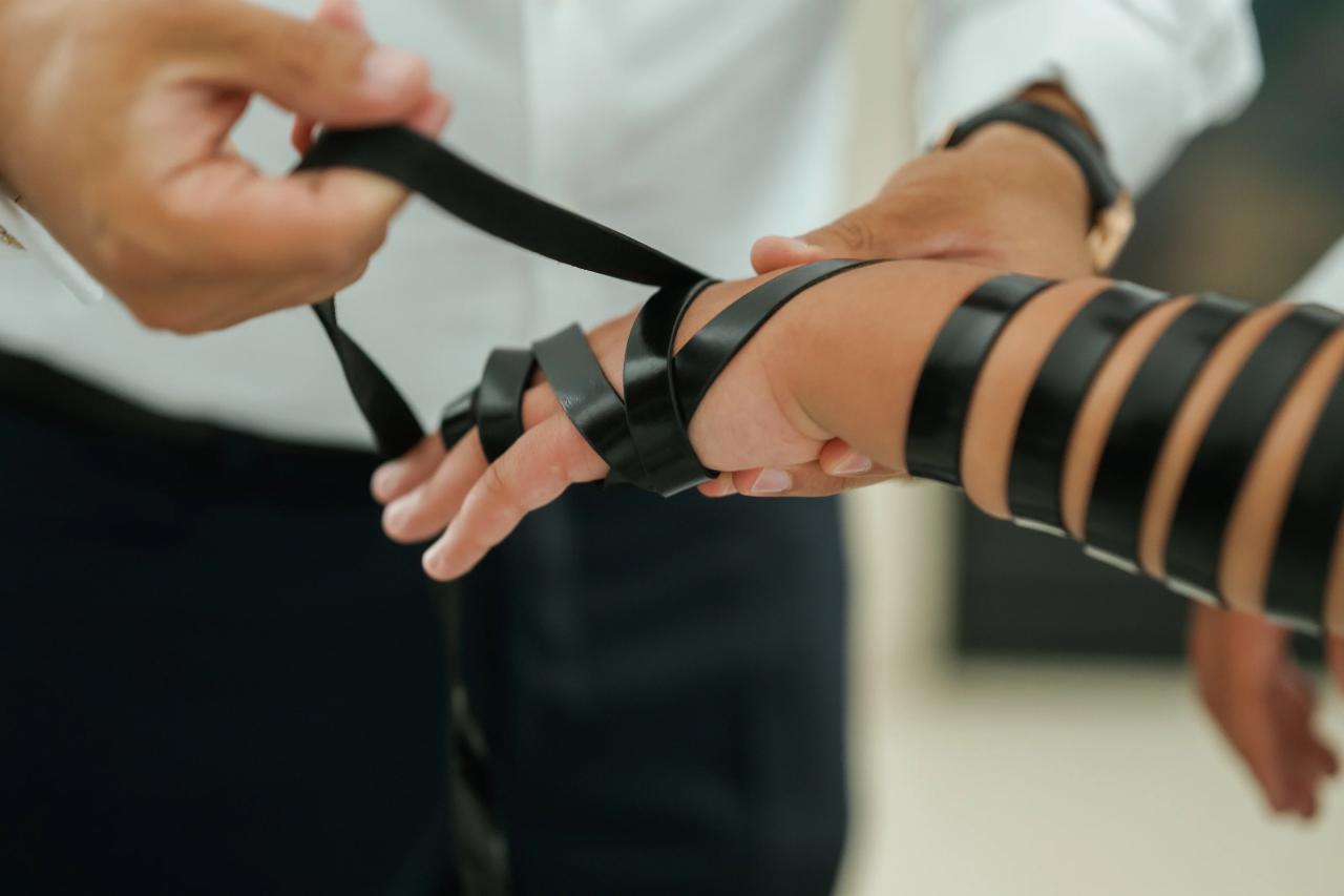 Close view of hands and tefillin straps during preparation, before the Eagle Ridge bar mitzvah. Bar Mitzvah photography.
