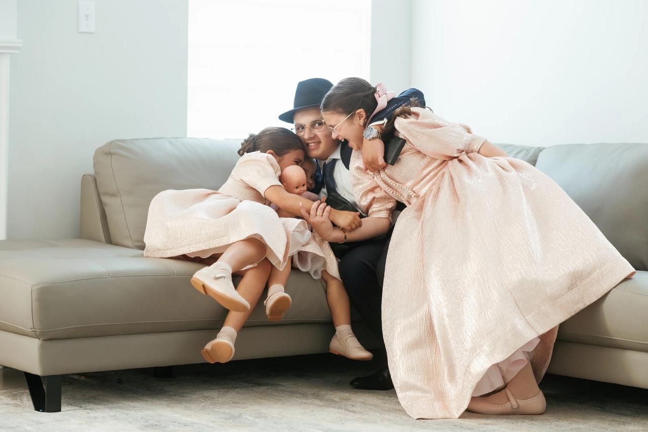 Siblings lean together on a couch for a close family photograph, before the Eagle Ridge bar mitzvah. Bar Mitzvah photography.