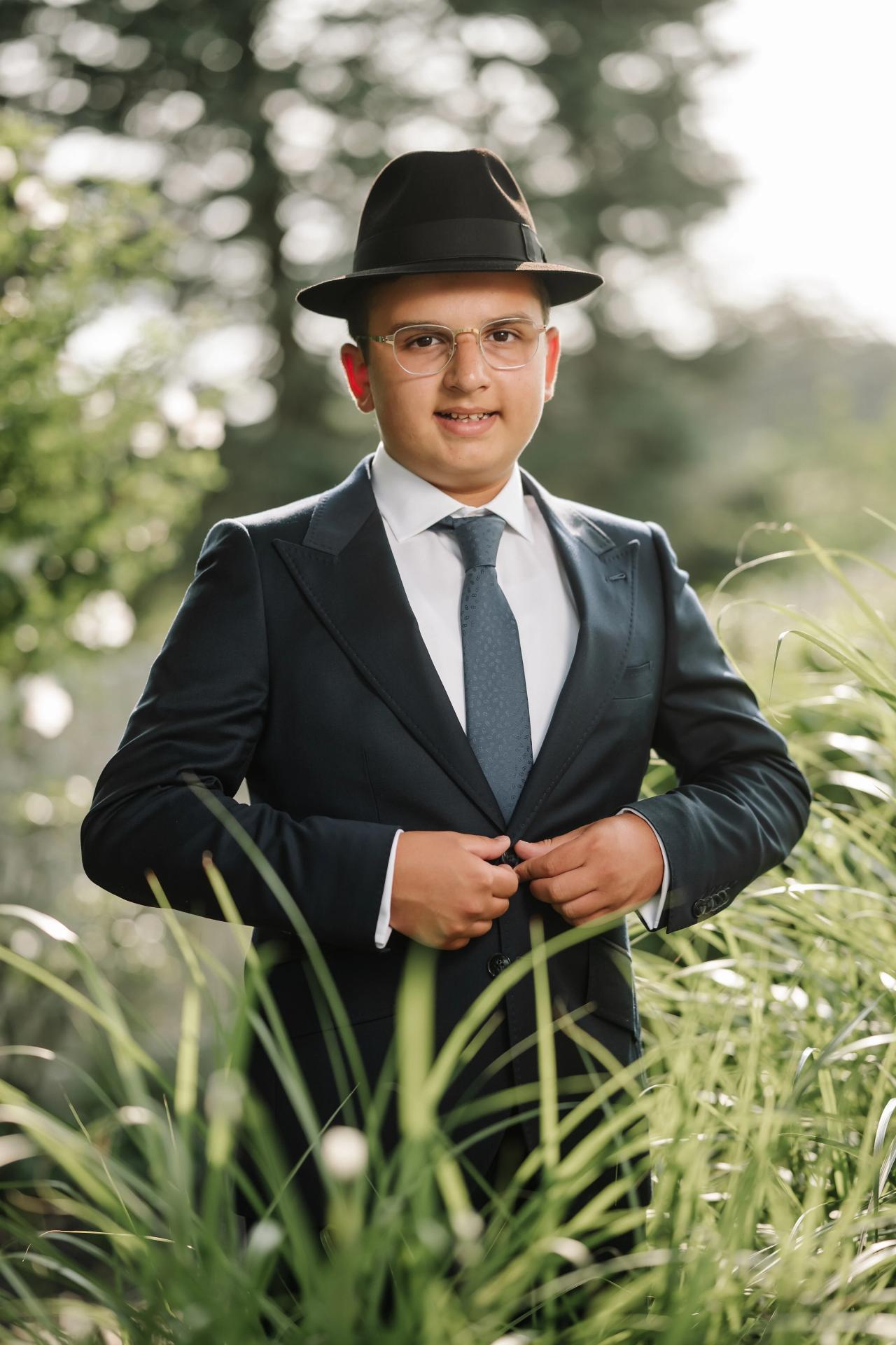 A close portrait of the celebrant framed by soft foreground grasses. Bar Mitzvah photography at Eagle Ridge, Lakewood, NJ.