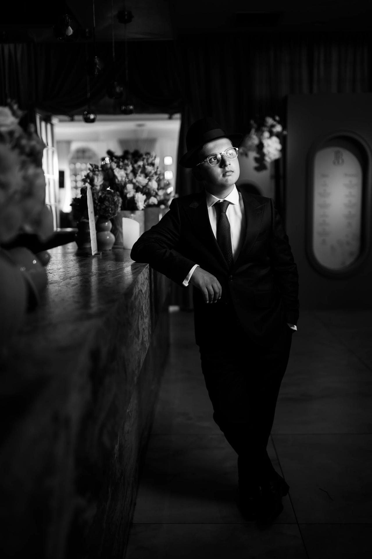 Black-and-white portrait of the celebrant with a soft floral foreground and mirrored light. Bar Mitzvah photography at Eagle Ridge, Lakewood, NJ.