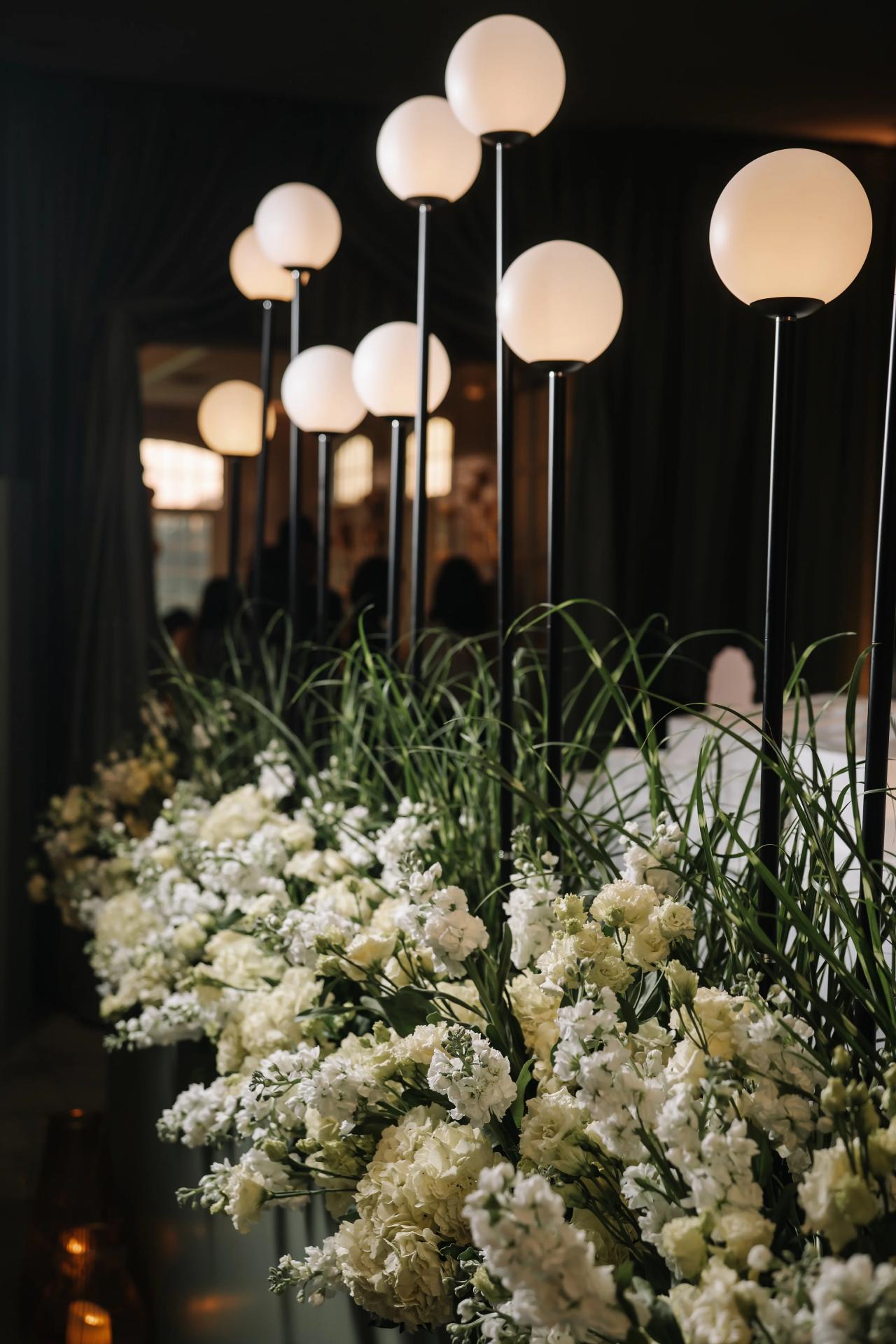 Glowing globe lights rise above white floral arrangements. Bar Mitzvah photography at Eagle Ridge, Lakewood, NJ.