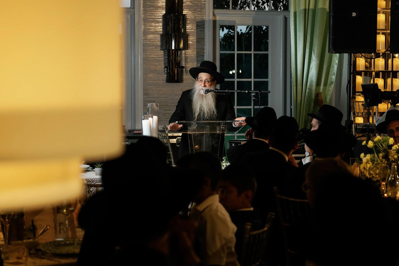 A speaker addresses the reception with seated guests in the foreground. Bar Mitzvah photography at Eagle Ridge, Lakewood, NJ.