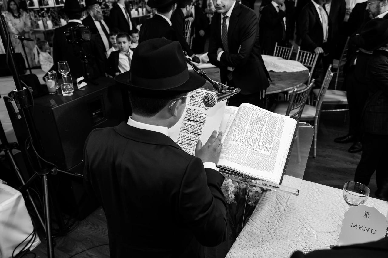 A black-and-white close view of the bar mitzvah boy reading from a book. Bar Mitzvah photography at Eagle Ridge, Lakewood, NJ.